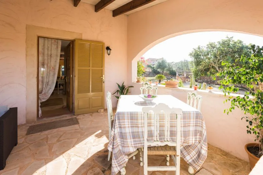 A covered outdoor dining area with a table overlooking a garden.