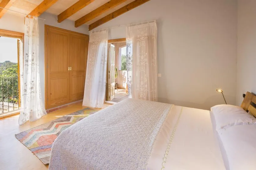 Un dormitorio con cama, armario de madera y puertas que dan a un balcón.