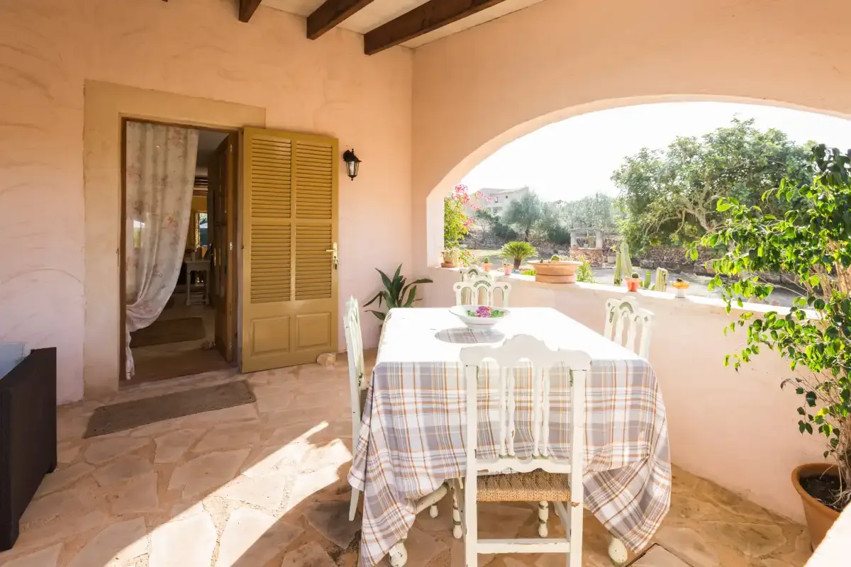Un patio cubierto con una mesa de comedor da a un jardín.