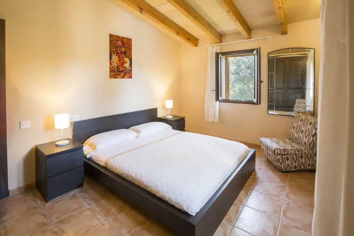 Dormitorio con una cama doble, mesitas de noche y una ventana.