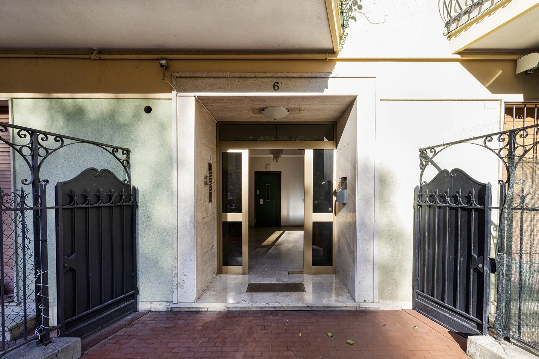 Una entrada enmarcada por portones metálicos abiertos conduce a un pasillo.