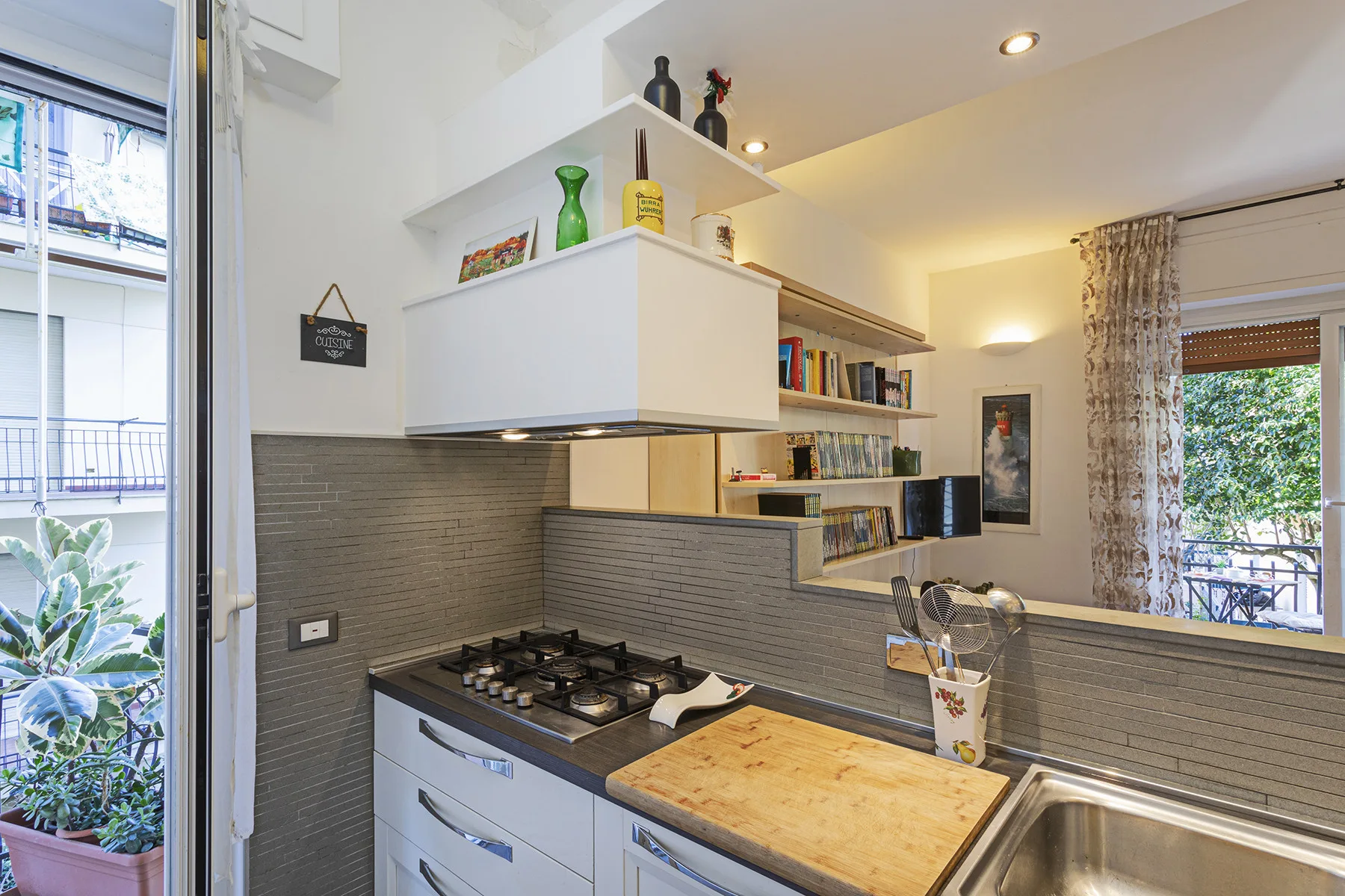 Una cocina moderna y luminosa con zona de cocción, encimera y ventanas grandes.