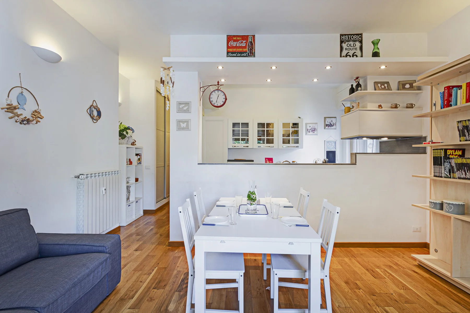Un comedor con una mesa blanca y sillas junto a una barra de cocina abierta.