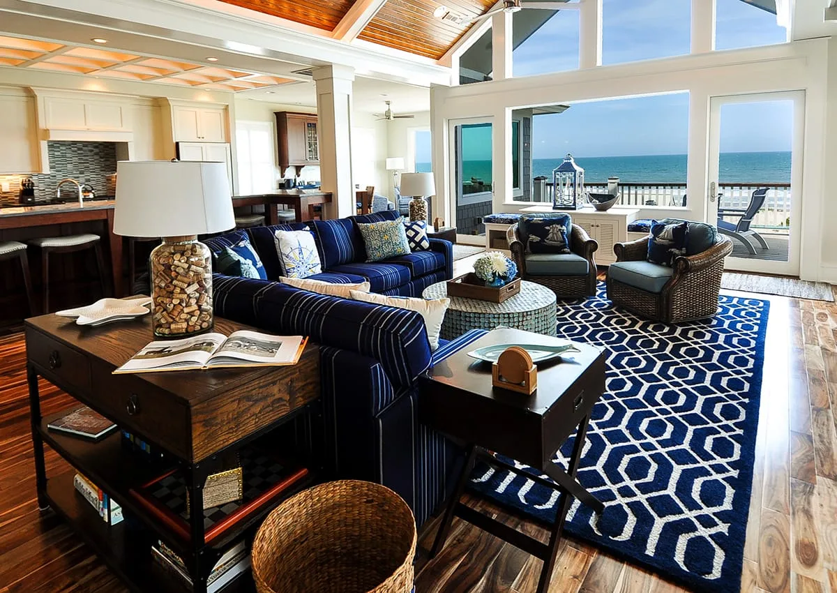 A spacious living room with blue seating and ocean views through large windows.