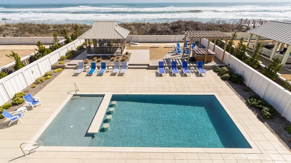 An outdoor pool area with lounge seating and the ocean visible beyond.