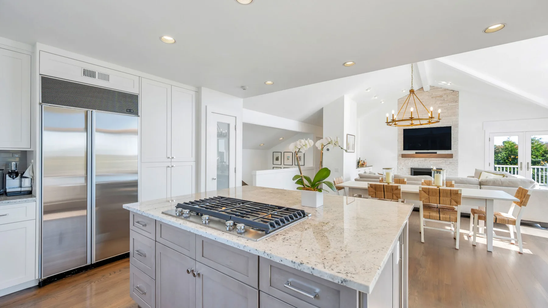 Una cocina luminosa cuenta con una gran isla central y un refrigerador de acero inoxidable.