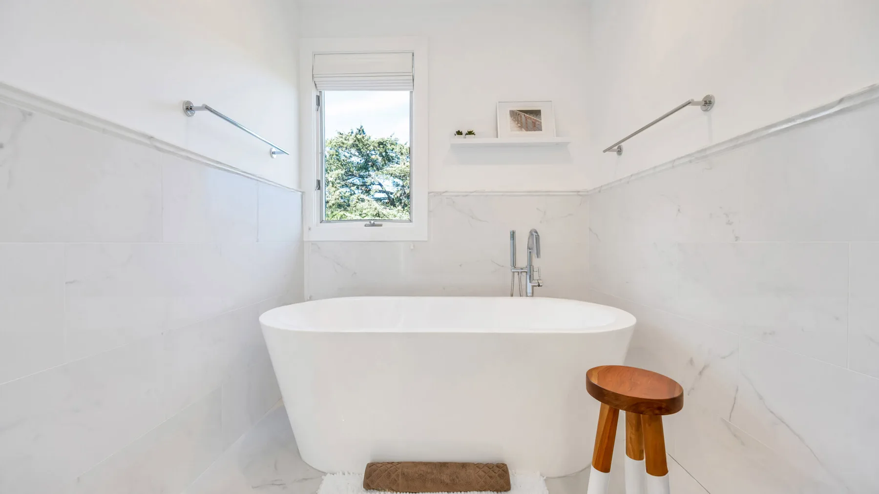 Un baño luminoso cuenta con una bañera exenta bajo una ventana.