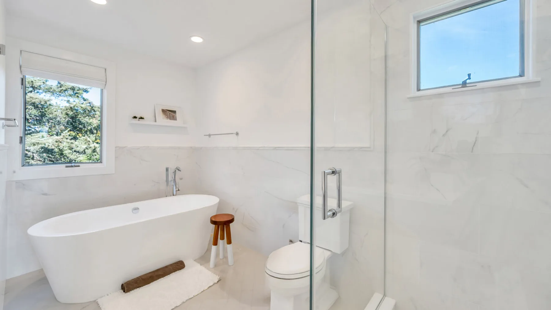 Un baño luminoso con bañera exenta y mampara de ducha de vidrio.