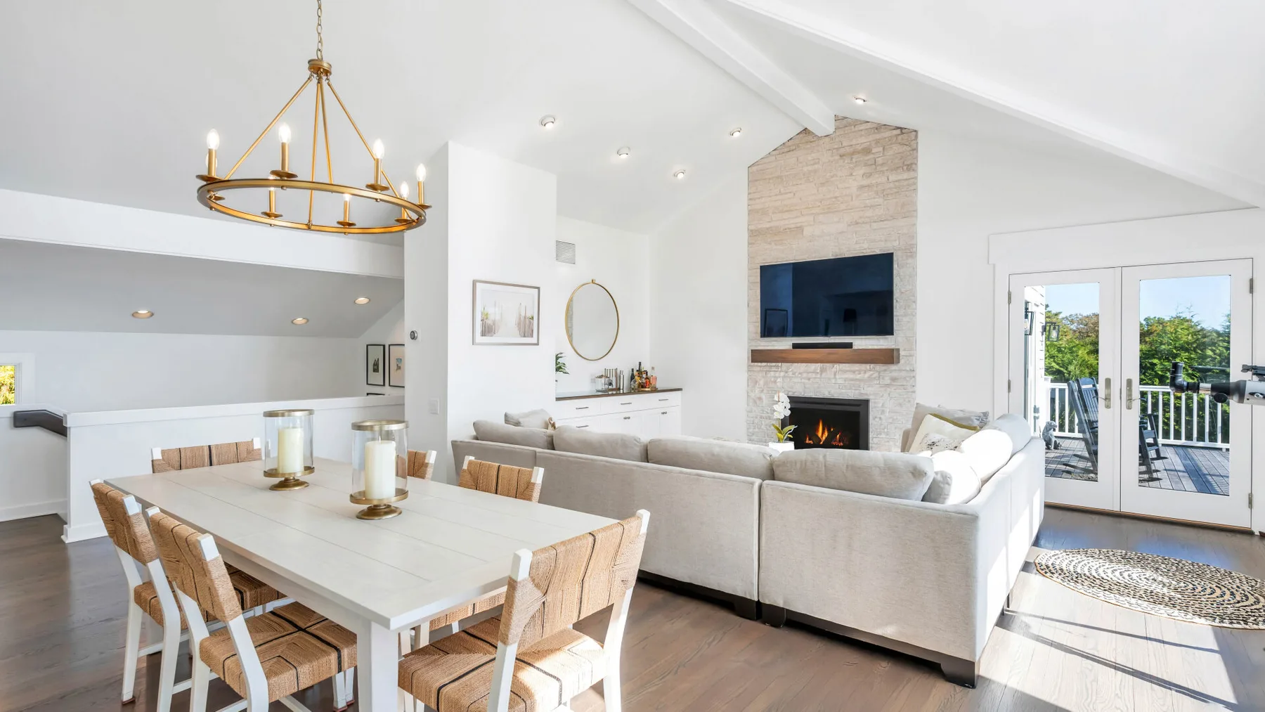 Una luminosa sala de estar y comedor diáfana con chimenea y puertas de vidrio.