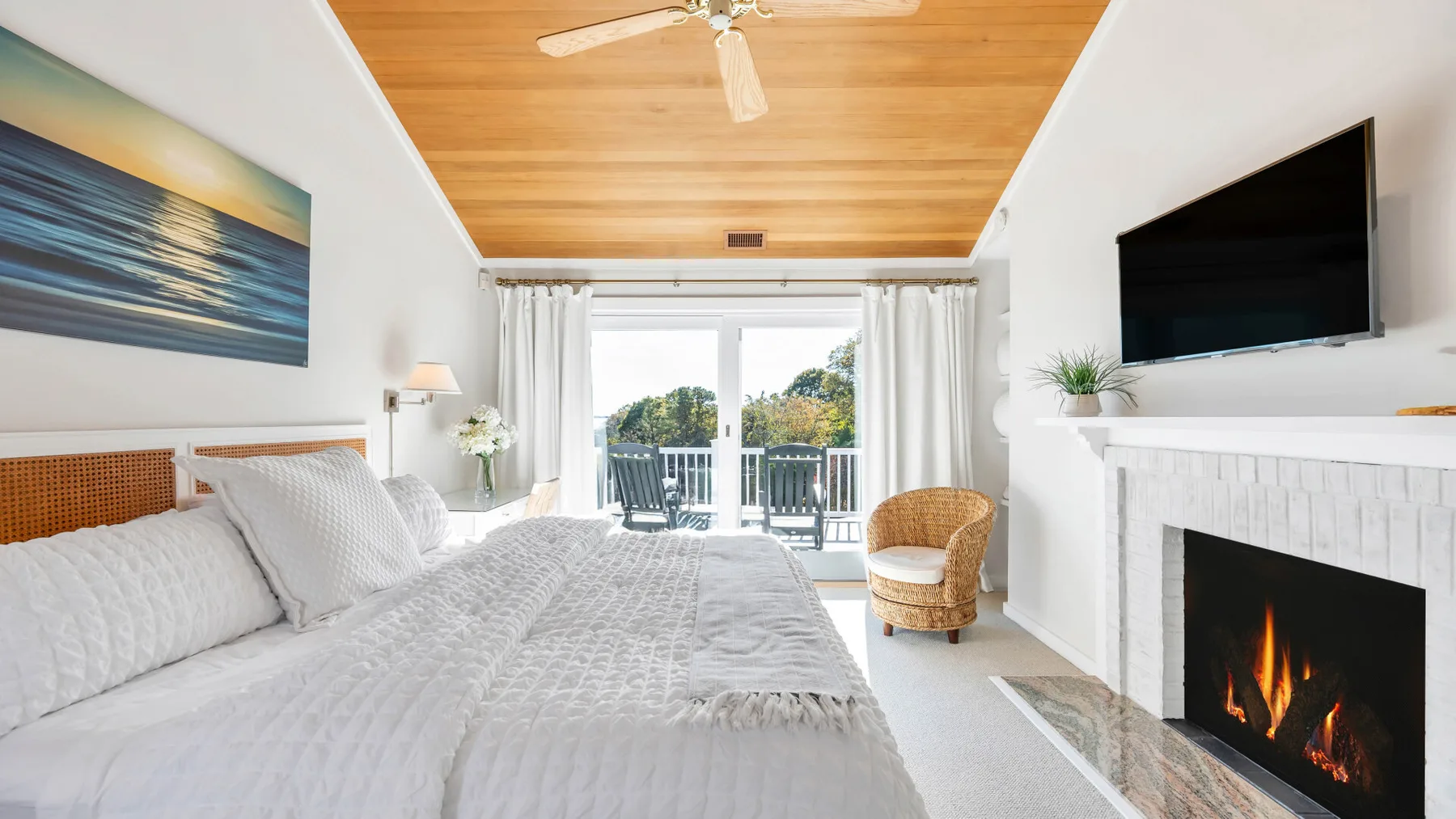 Un dormitorio luminoso con una cama grande, una chimenea y puertas que dan a un balcón.