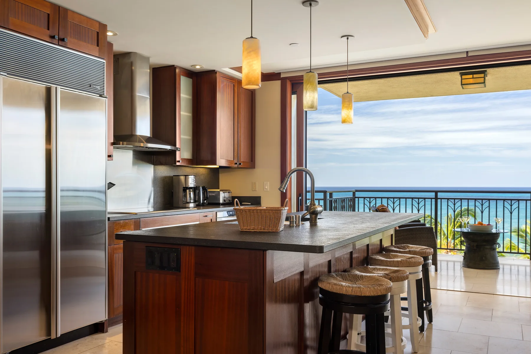 Una cocina con isla central y asientos de barra se abre a un balcón.