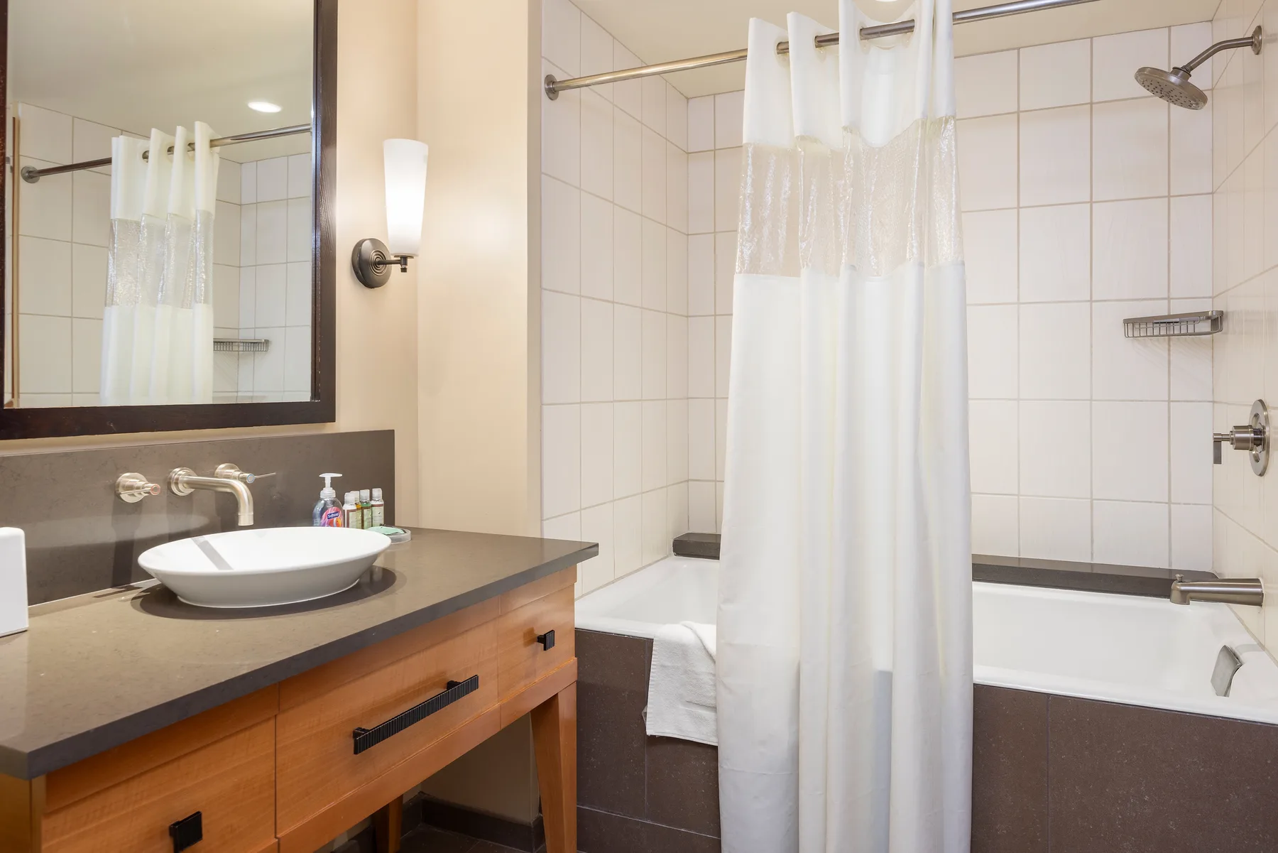 Un baño con azulejos, bañera, cortina de ducha y lavabo.