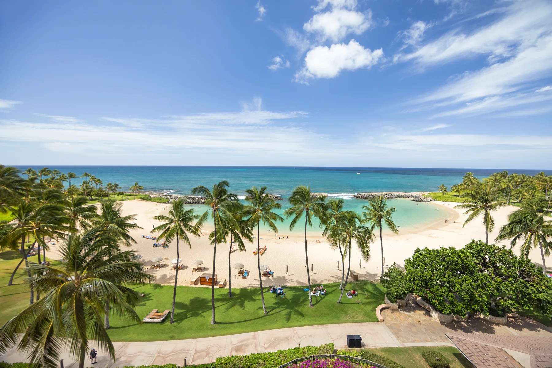 Una playa tropical con palmeras, agua turquesa y una costa ajardinada.