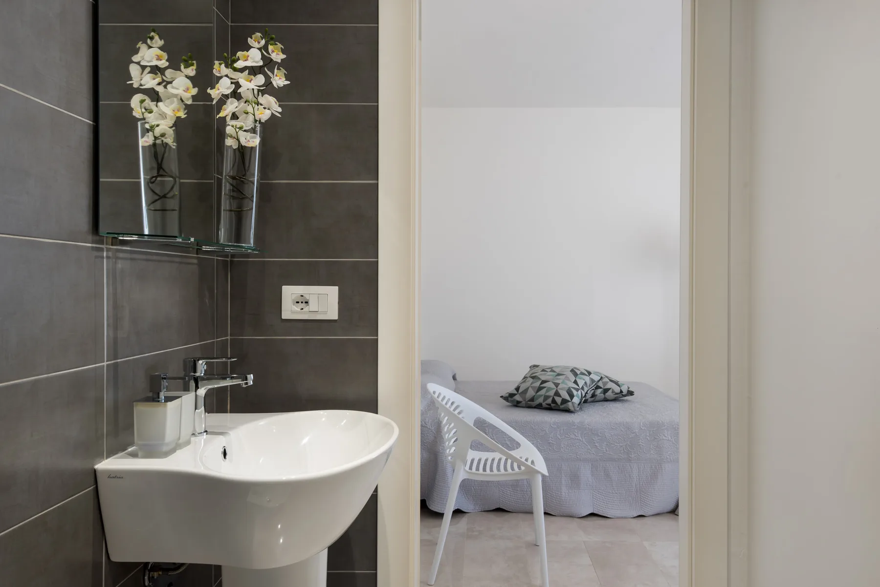 A bathroom sink beside an open doorway looking into a bedroom.