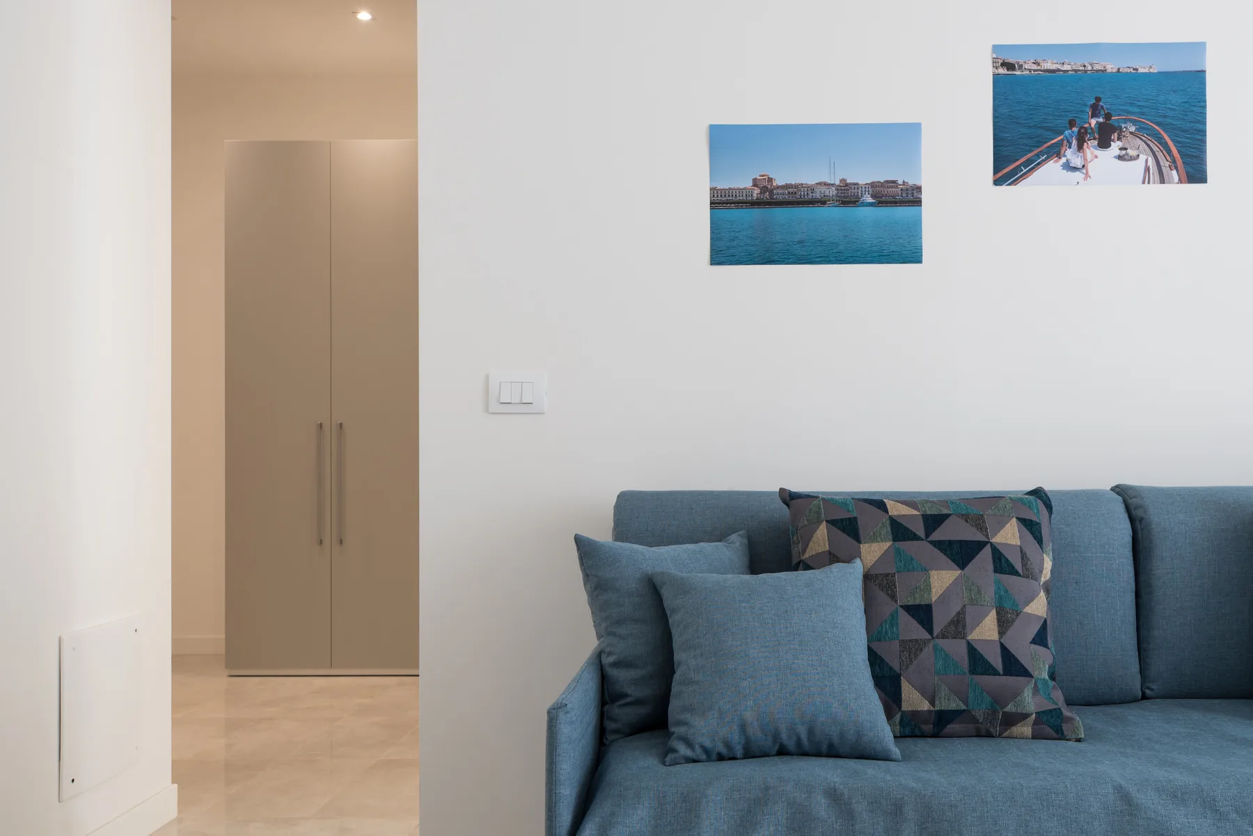 A living room with blue seating beneath two framed pictures.