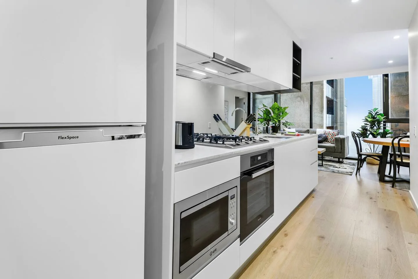 Una cocina moderna se abre a un comedor, con un refrigerador junto a la encimera.