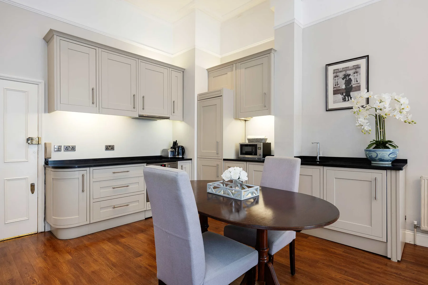 Una cocina y comedor luminosos con gabinetes claros y una mesa redonda.