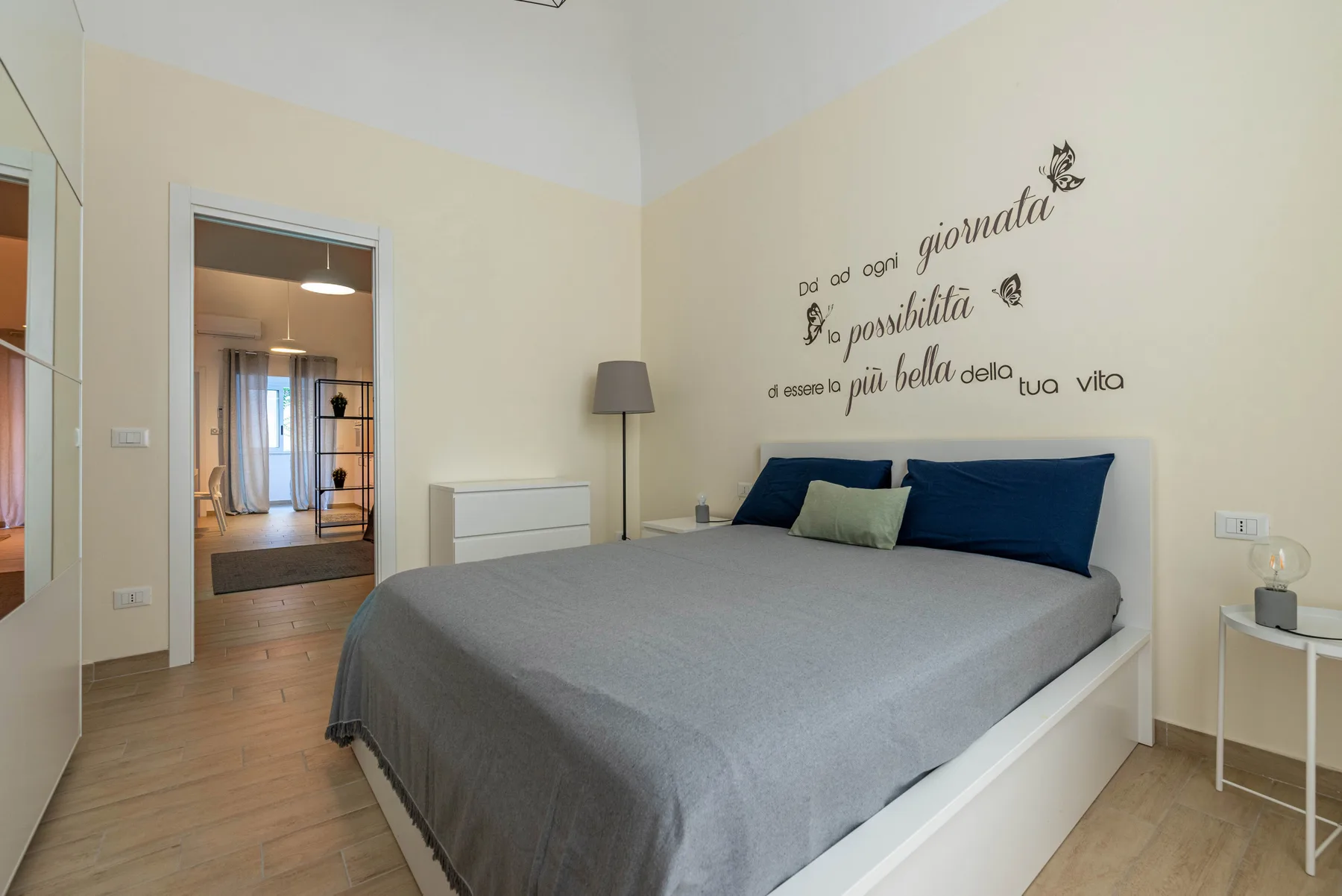 A bedroom with a large bed and decorative lettering on the wall.