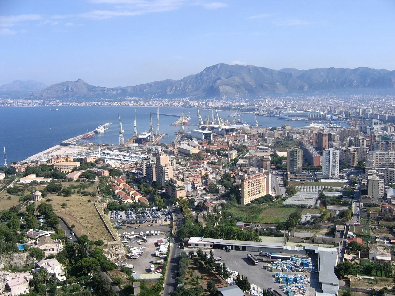 A coastal city and harbor spread beneath a mountain range.