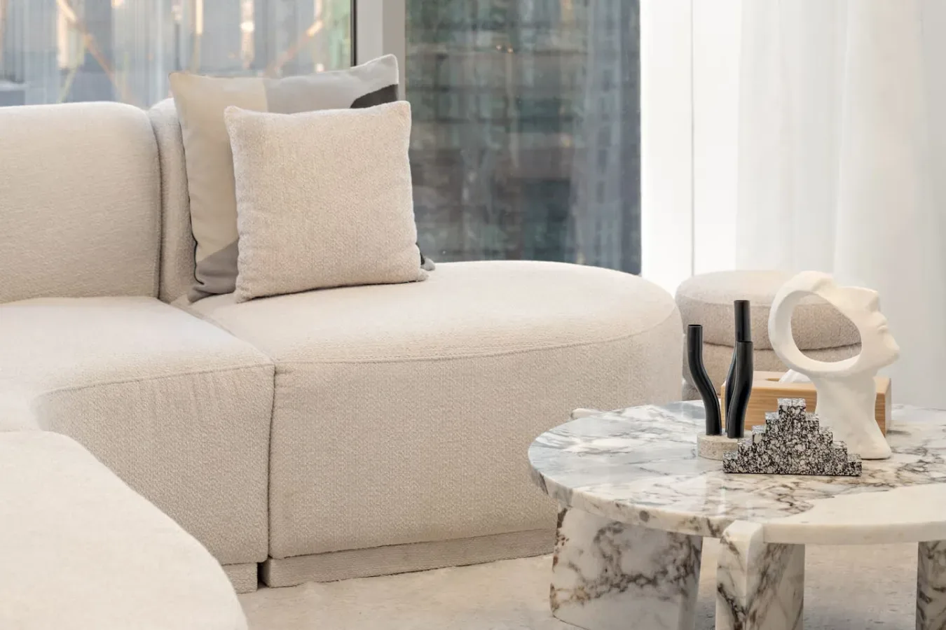 A bright living room with a light-colored sofa and a marble coffee table.