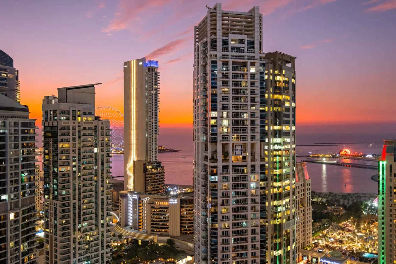 Horizonte urbano al atardecer, con edificios altos iluminados junto al agua.