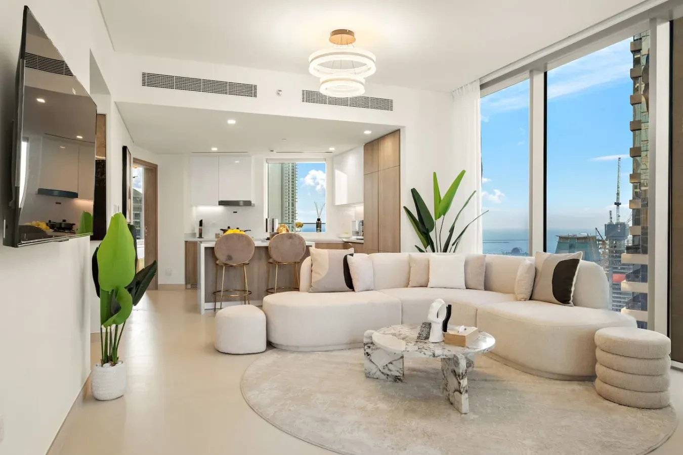 A bright living room with curved seating and large windows overlooking the water.