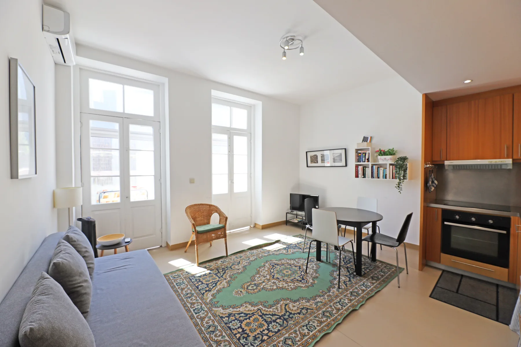 A bright living and dining area has seating, a table, and an adjoining kitchen.