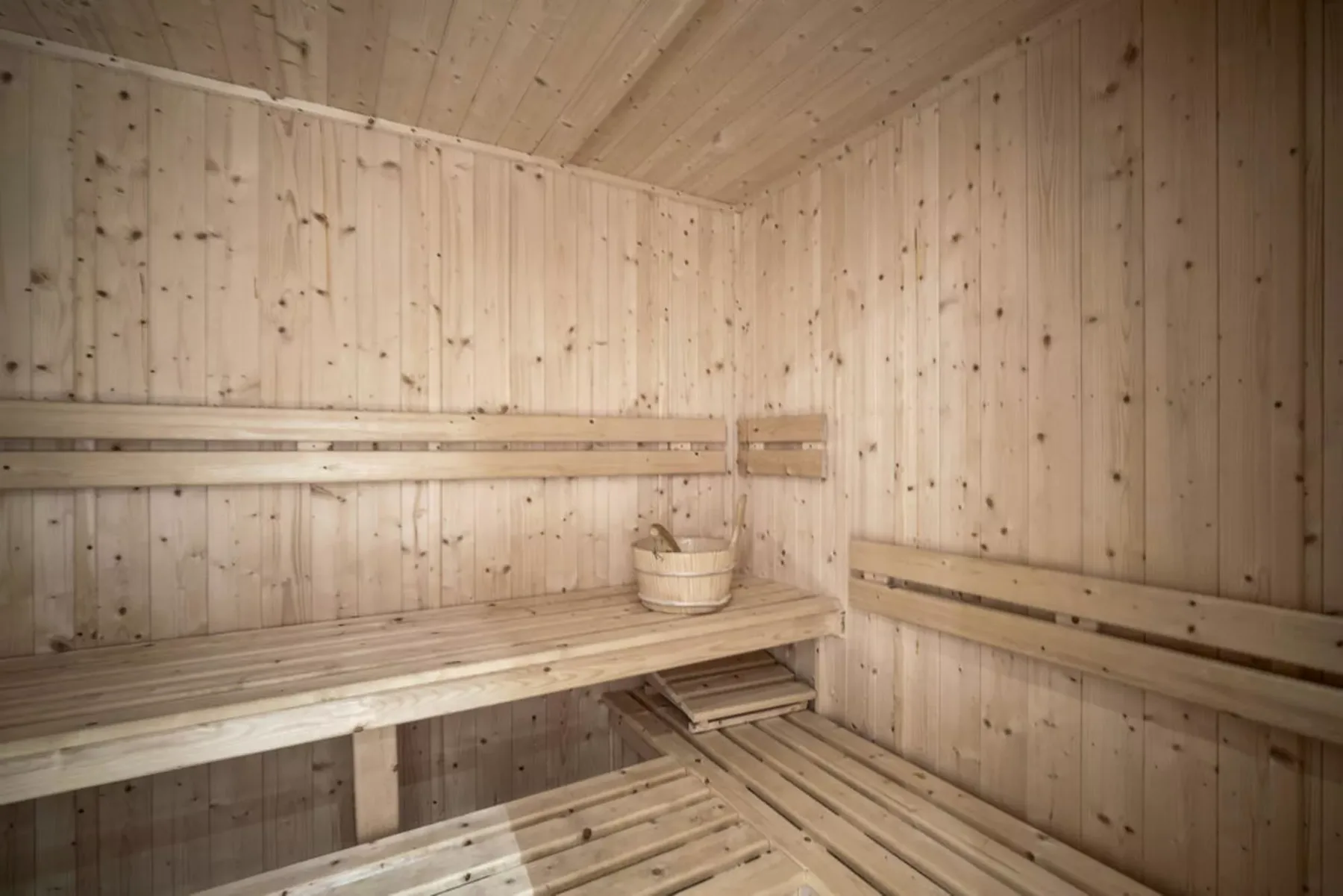 A wood-paneled sauna room with tiered wooden seating.