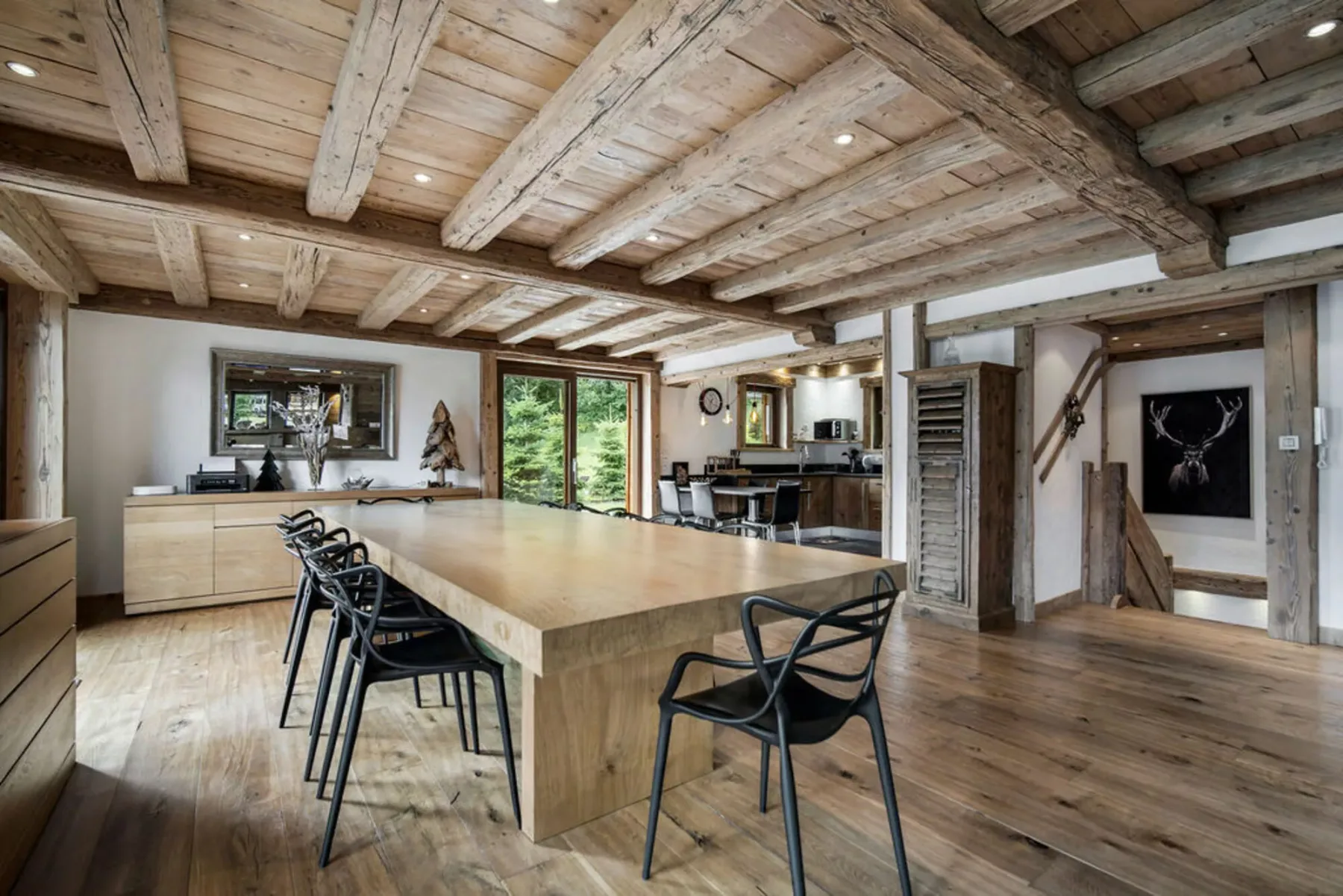 A spacious kitchen and dining area with a large island beneath exposed wooden beams.