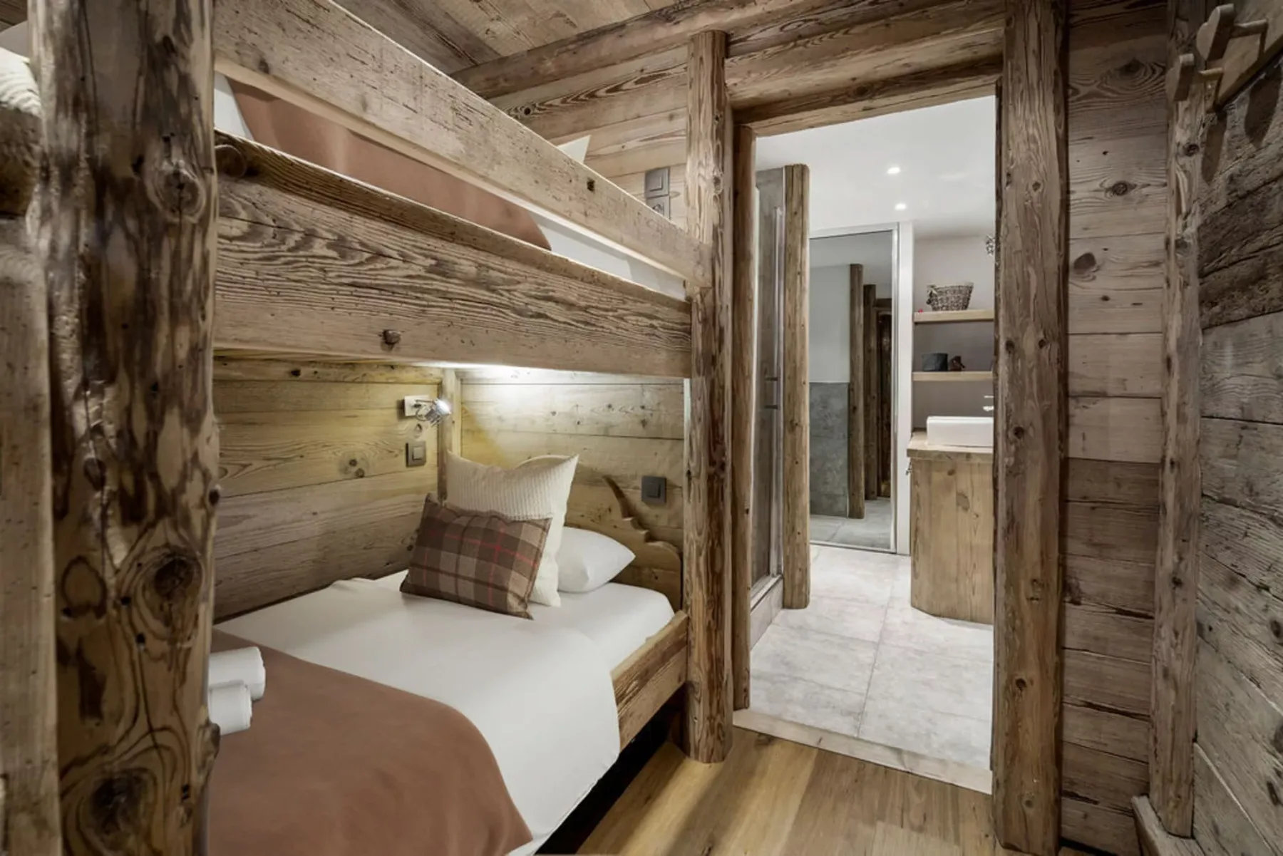 A rustic bedroom with a wooden bunk bed beside an open doorway.