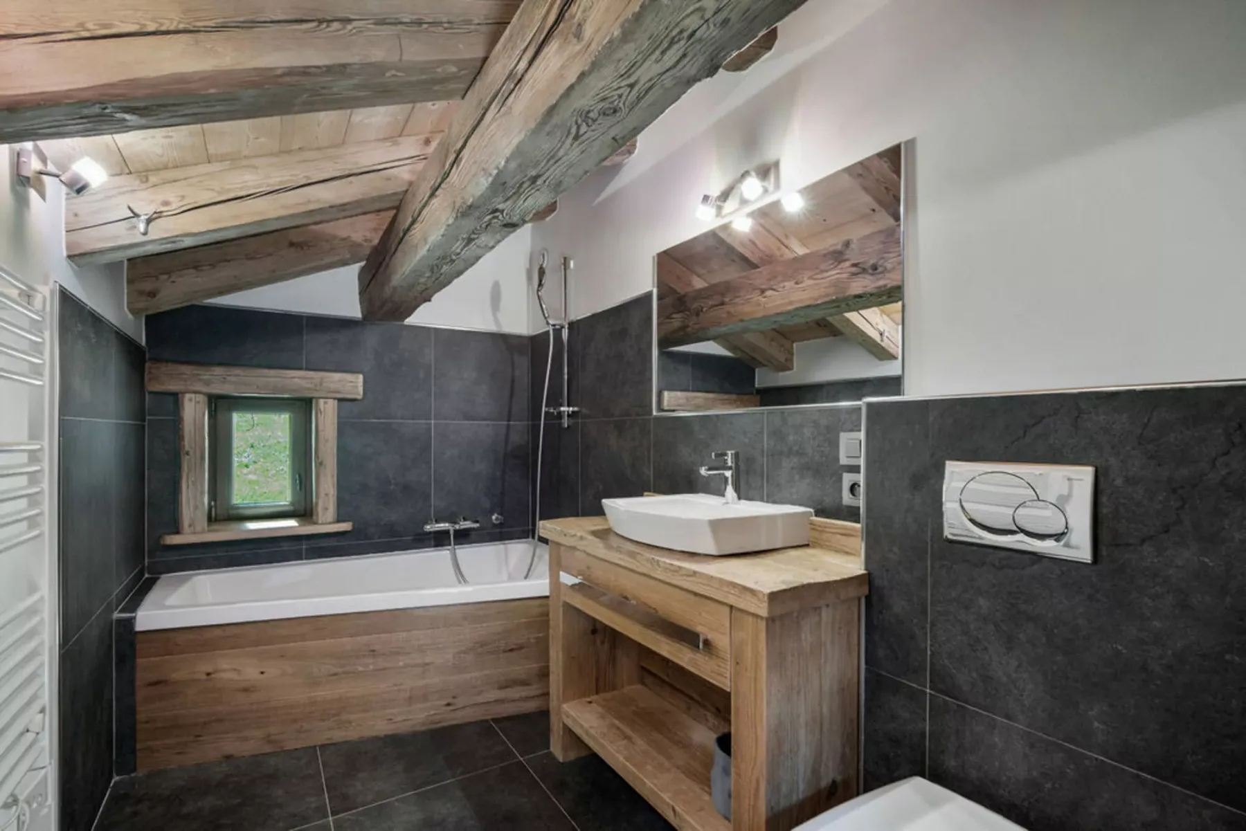 A bathroom with a bathtub, sink, and exposed wooden ceiling beams.