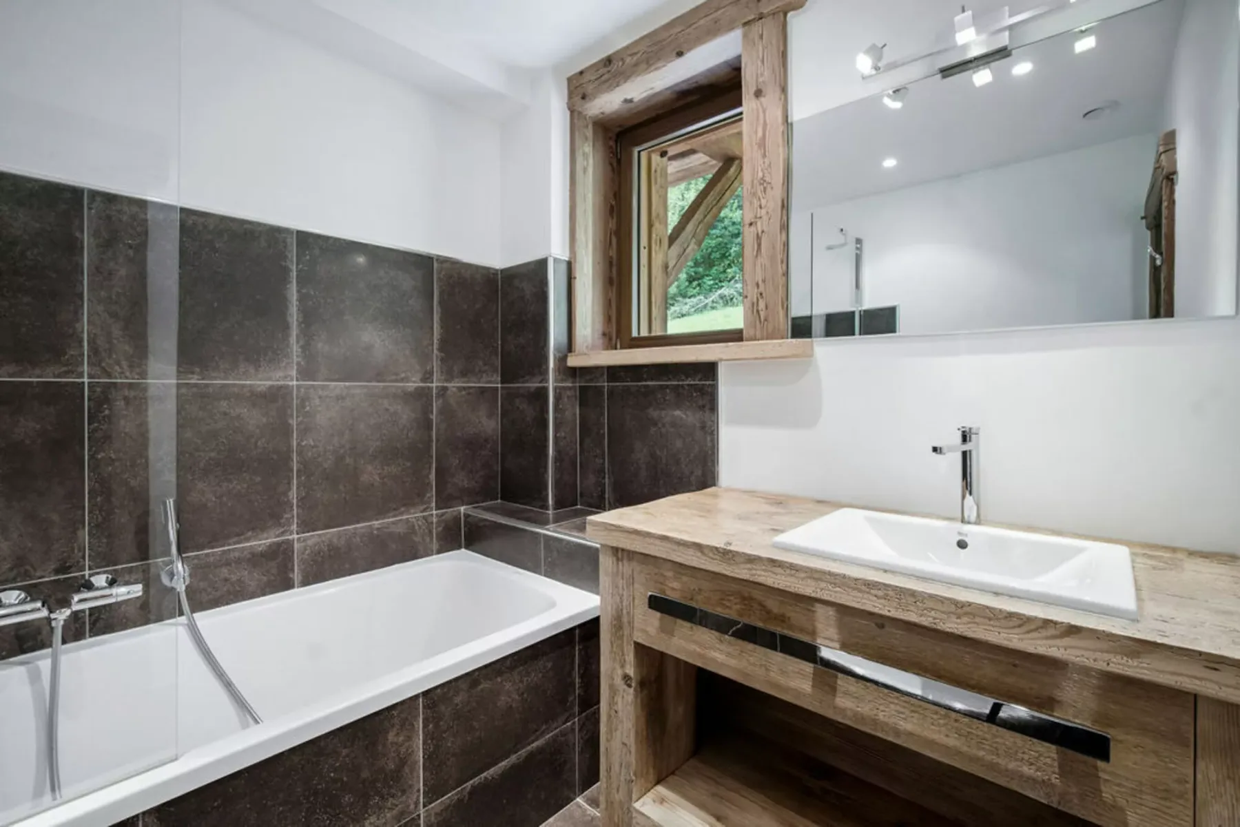 A bathroom with a bathtub, sink, and wood-framed mirror.