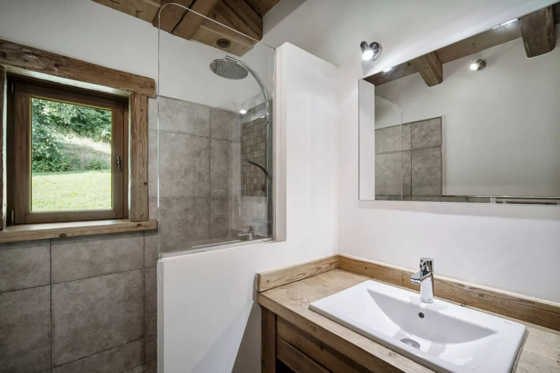 A bathroom with a shower, window, and sink.