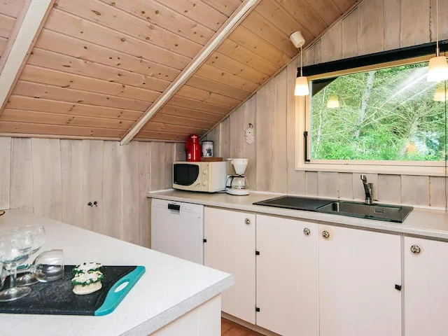 A kitchen with a countertop, sink, and window overlooking greenery.