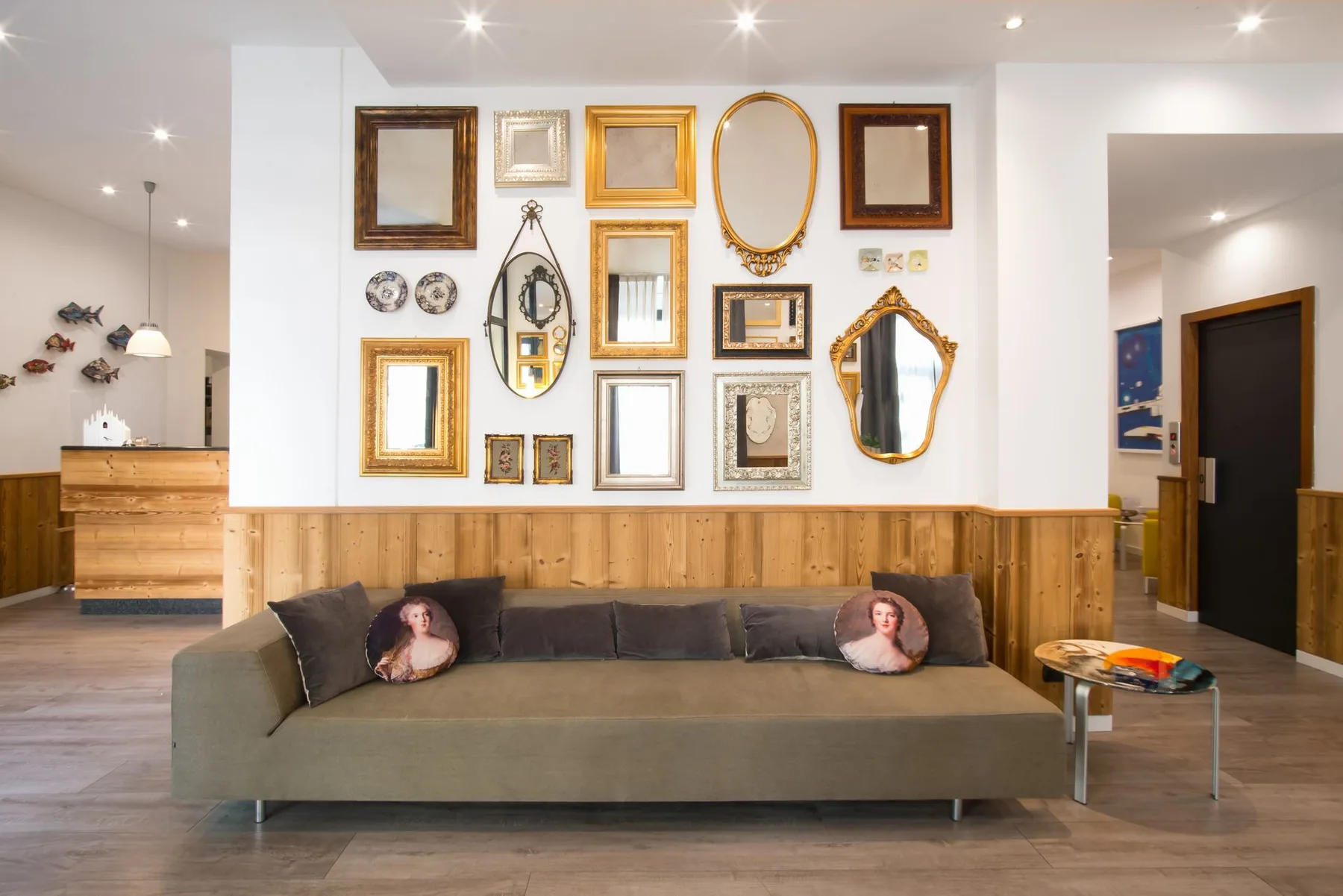 Reception area with a sofa, mirrors, and wood paneling.