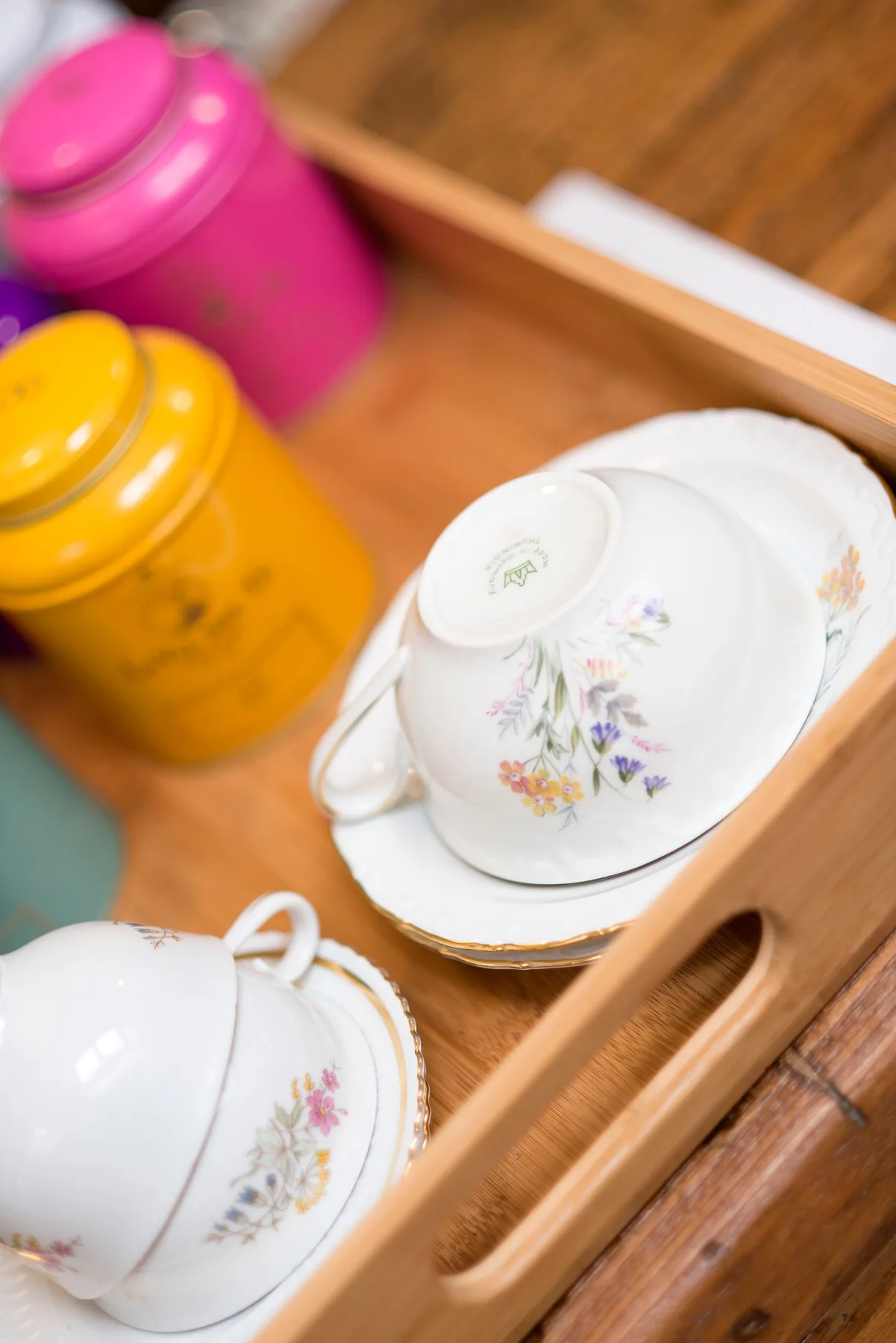 Tea cups and tea tins arranged on a wooden tray.