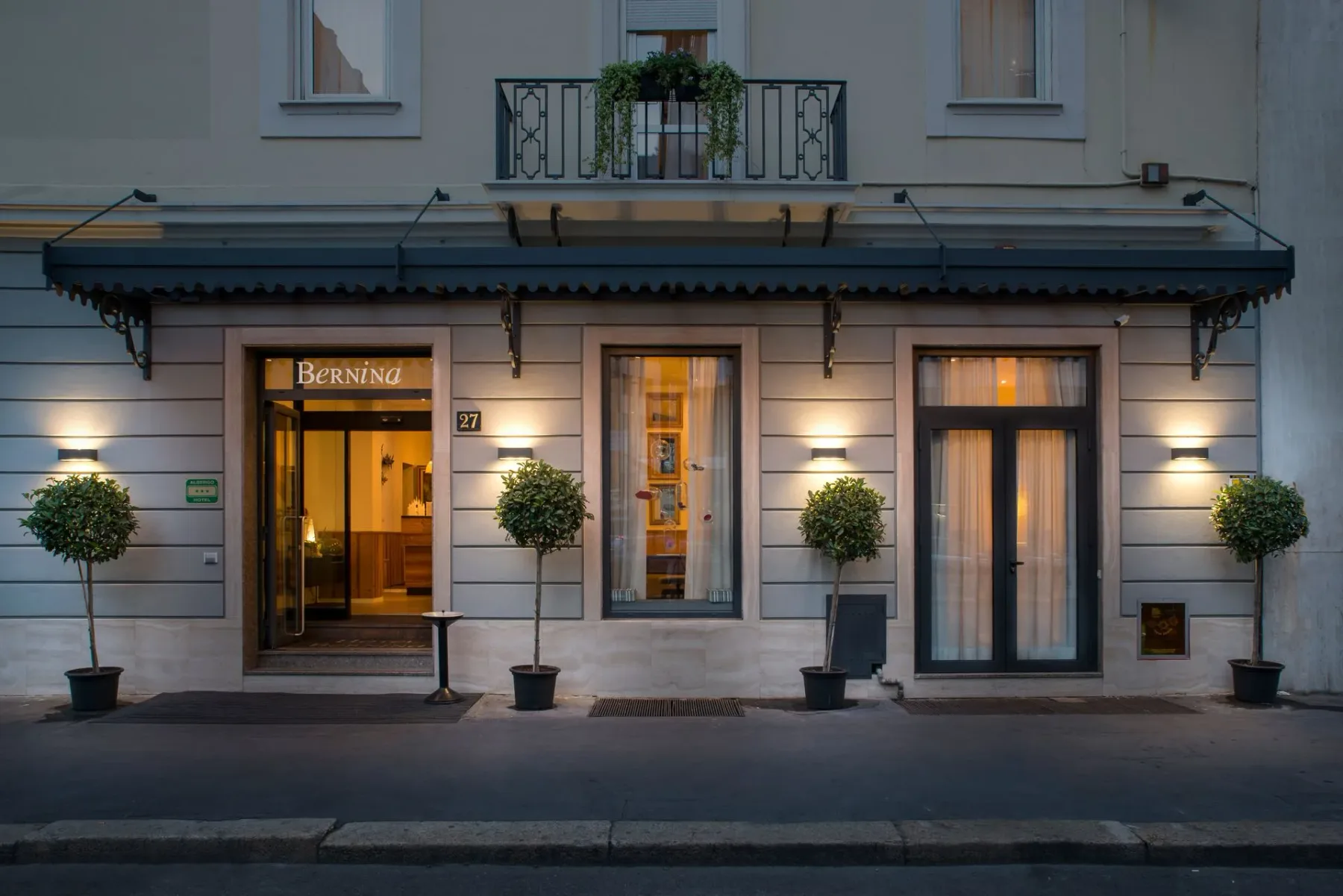 Hotel entrance with awning and small trees beside the doors.