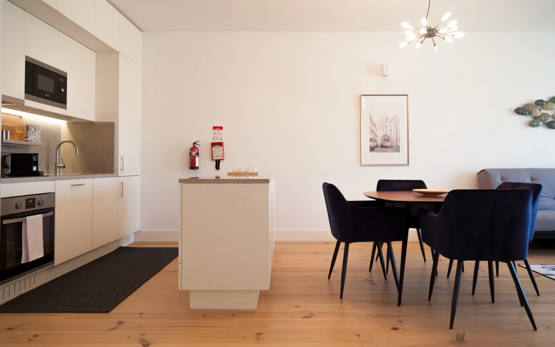 Una luminosa cocina abierta al comedor, con una mesa y asientos oscuros.