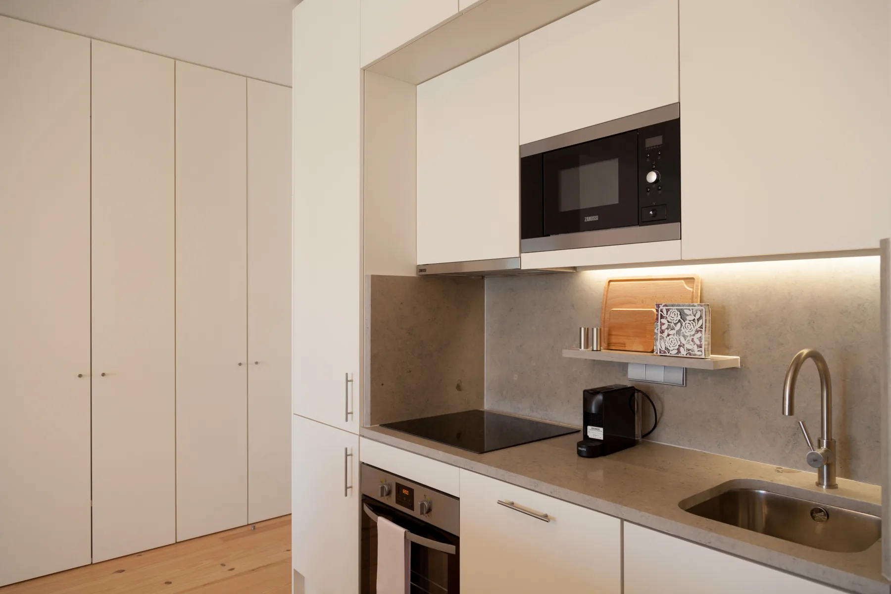 A modern kitchen with white cabinets, a countertop, and built-in appliances.