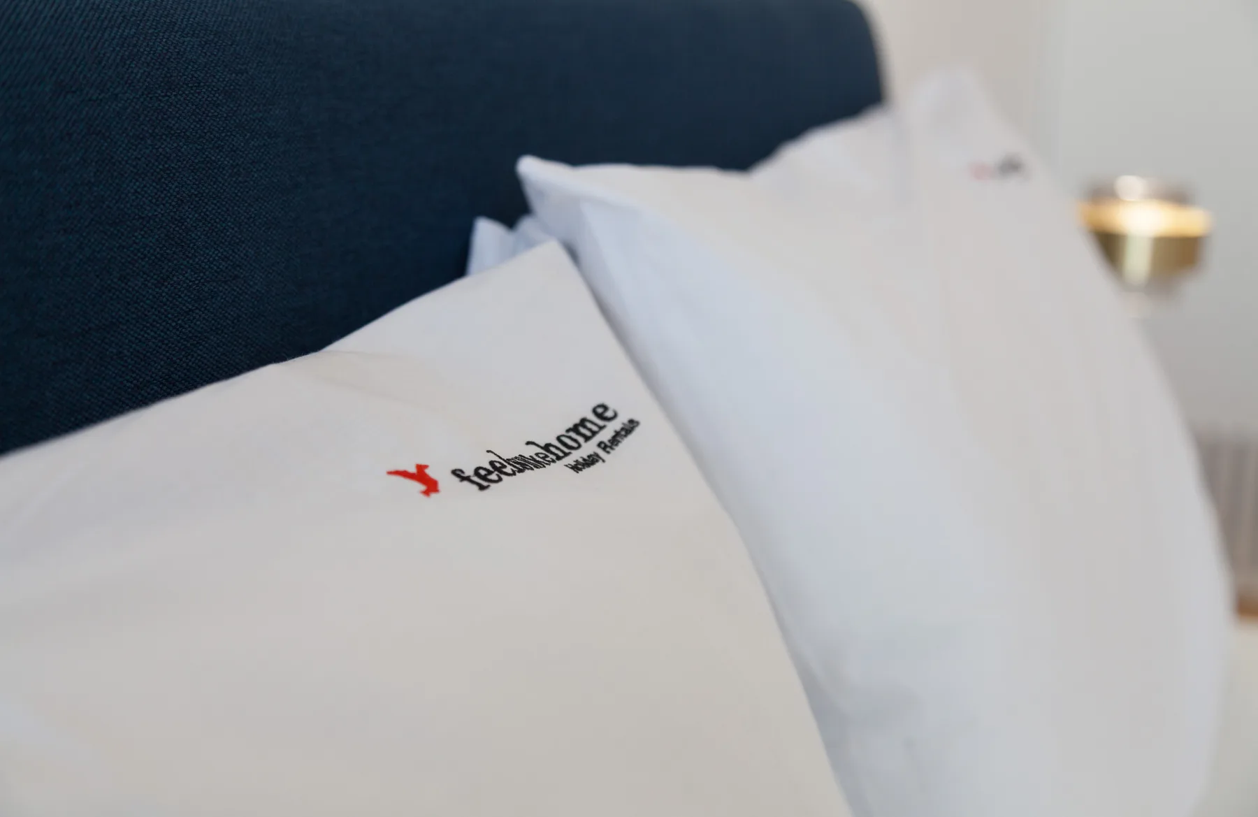 Close-up of white pillows against a dark upholstered headboard.