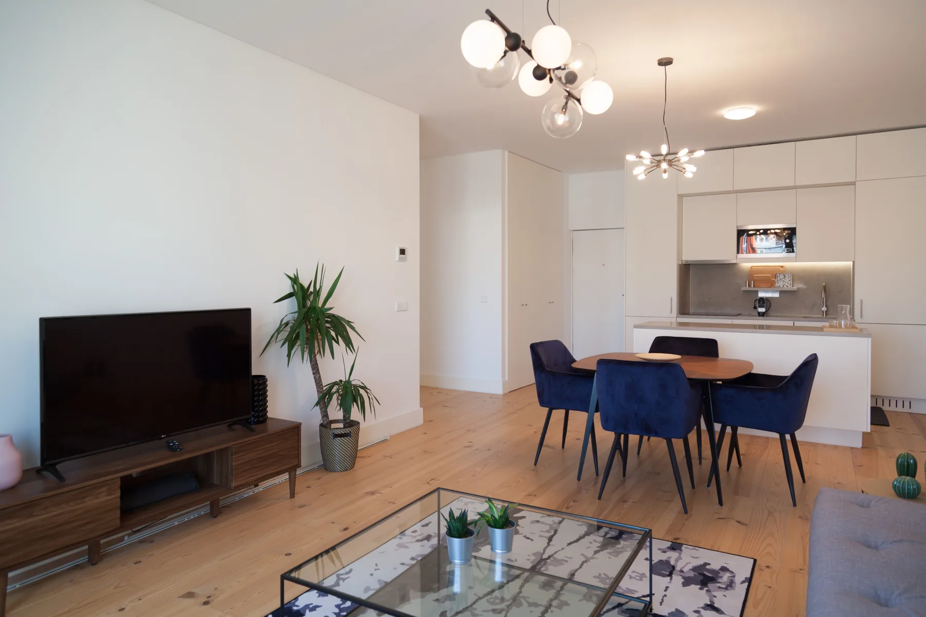 Una luminosa sala de estar y comedor se abre a la cocina, con un televisor y una mesa.
