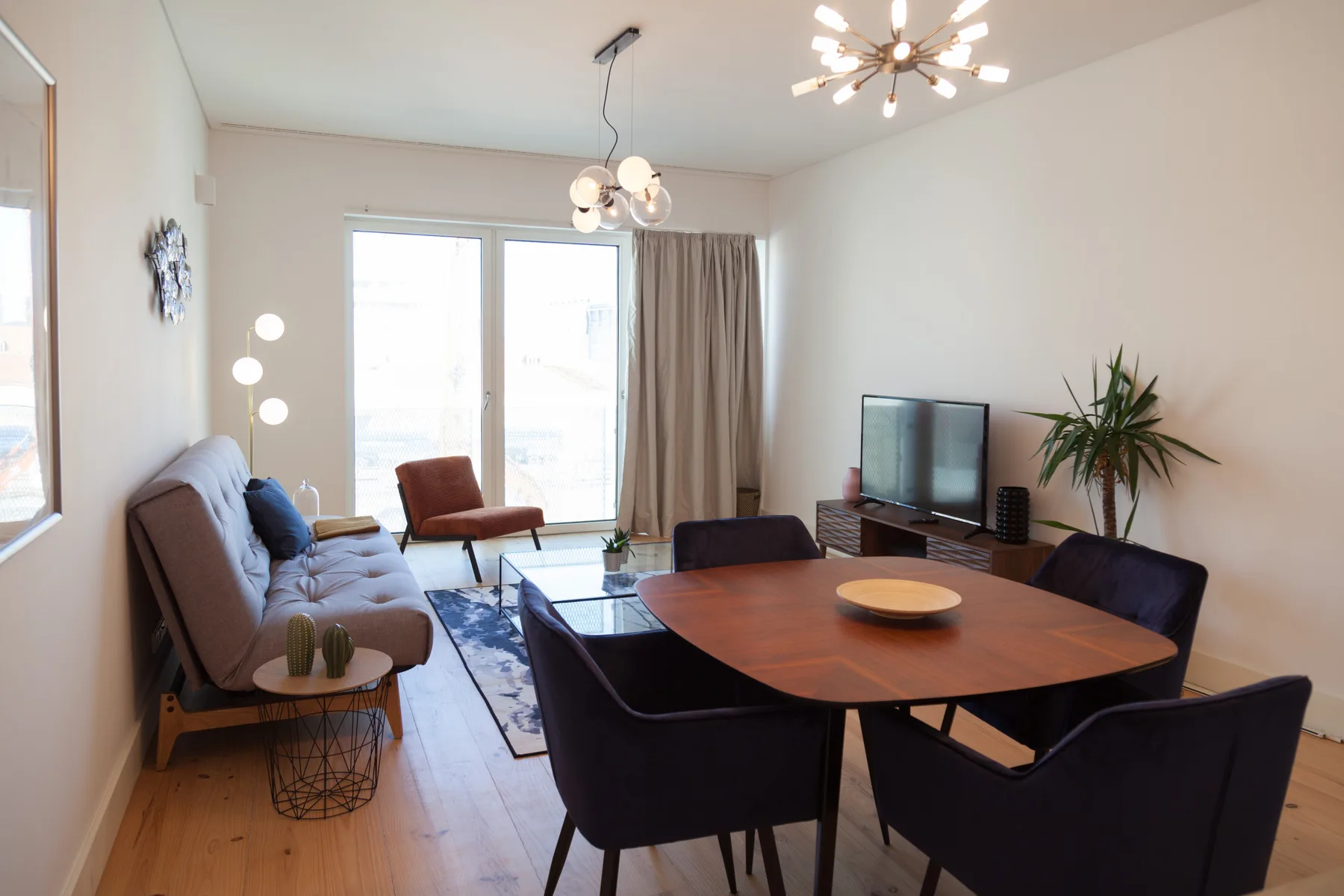Sala de estar con mesa de comedor, asientos y un televisor junto a la ventana.