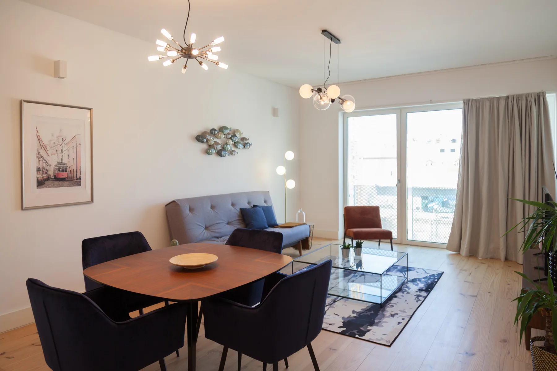 A bright living room with a dining table and seating beside large windows.