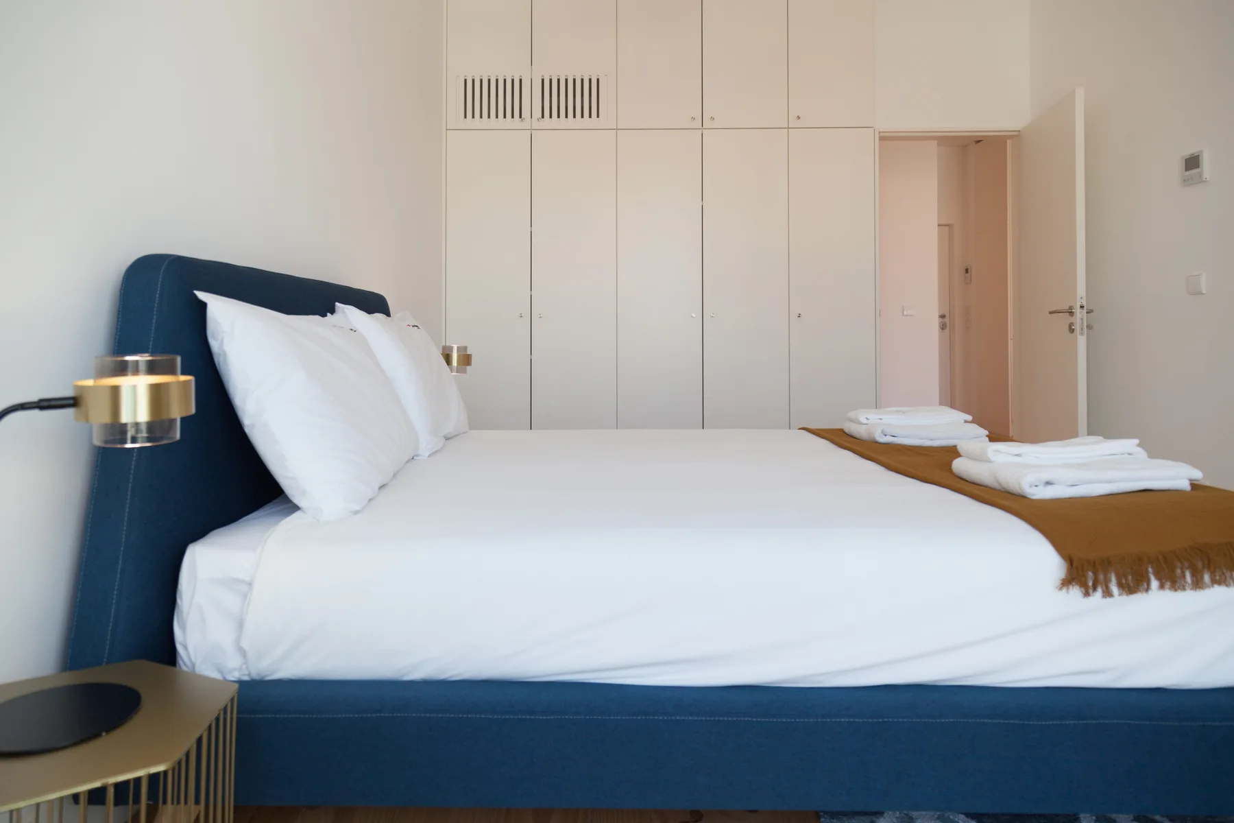 A bedroom with a neatly made bed and folded towels.