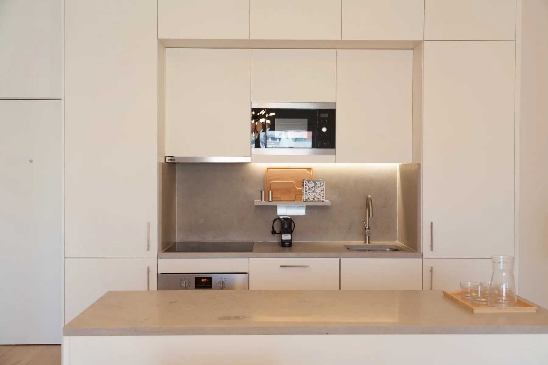 A modern kitchen with white cabinetry and a countertop.