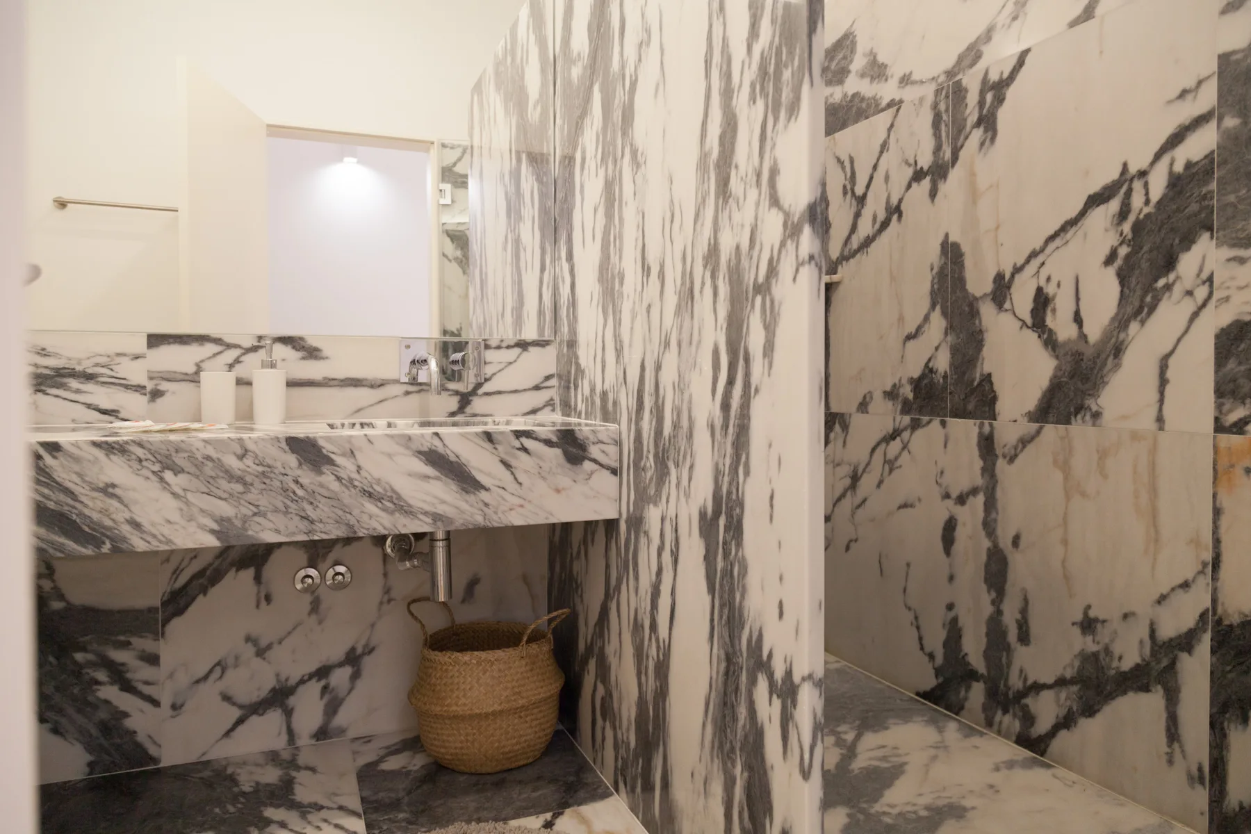 A marble bathroom with a sink and a walk-in shower.
