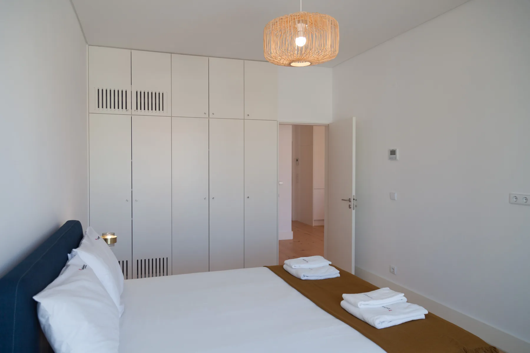 A bedroom with a bed, built-in cabinets, and an open doorway.