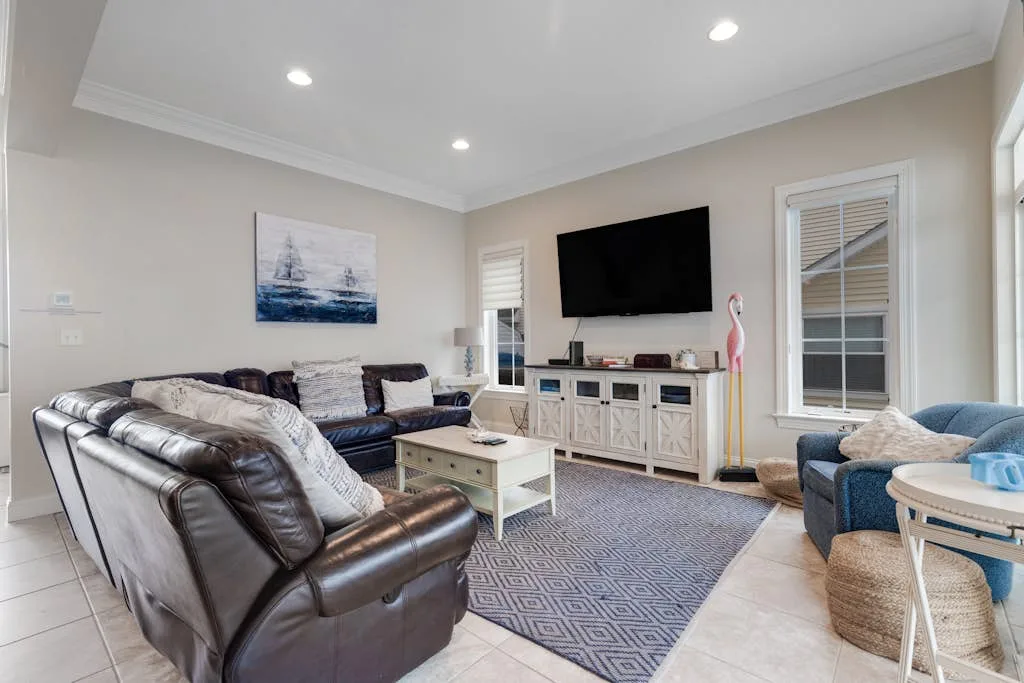 A living room with leather seating, a television, and a patterned rug.