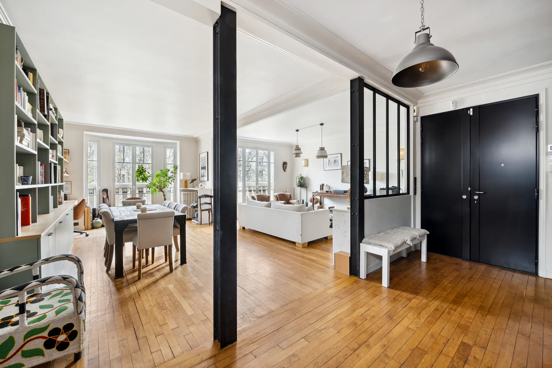 Una sala de estar y comedor de planta abierta con suelo de madera y un tabique negro.