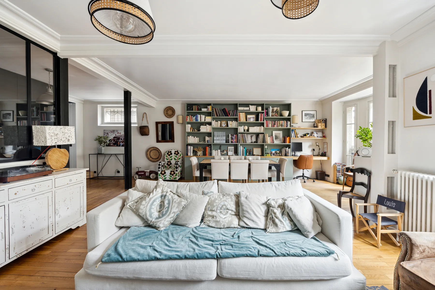 Una sala luminosa con un sofá blanco frente a una pared de estanterías.